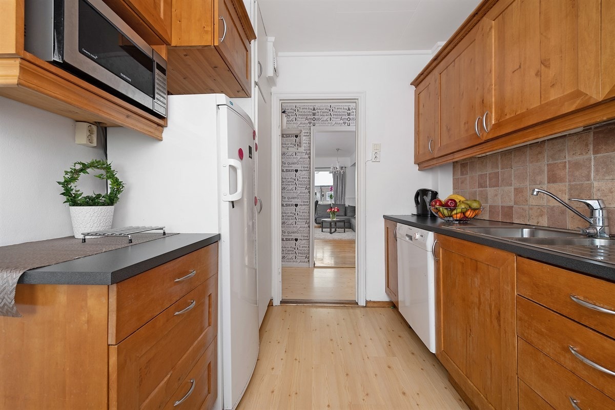 Leiligheten har et separat og funksjonelt kjøkken. Innredningen har profilerte fronter i tre, fine topplister, vitrineskap og mørk laminatbenkeplate med nedfelt oppvaskkum. Galleribilde