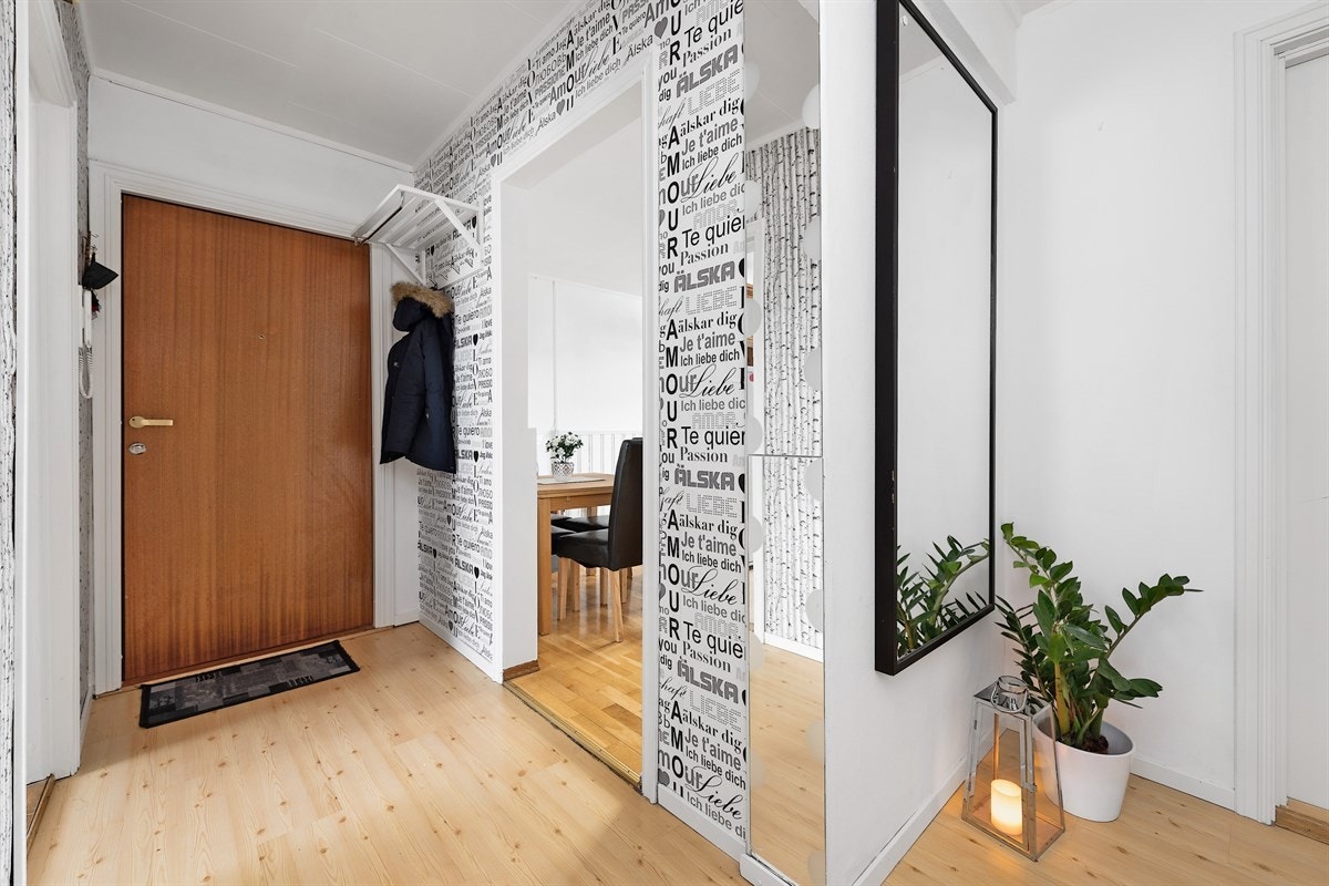 Boligens entré er lys med laminatgulv og tapetserte vegger med fine mønstre. Entreen har i dag åpen garderobeløsning, men det er rom for å sette inn garderobeskap innover i gangen om man ønsker mer lagringsplass. Galleribilde