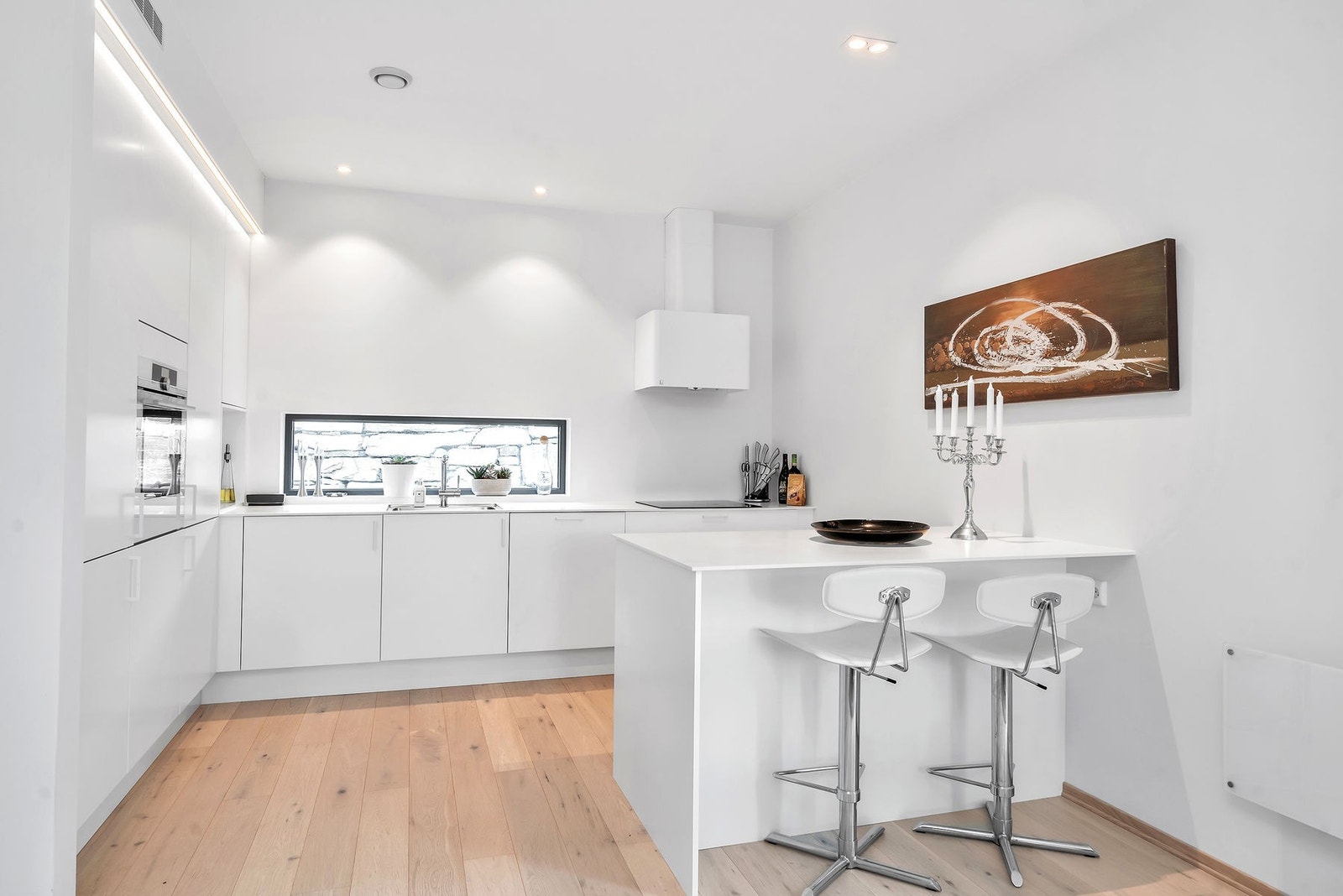 Eneboligen har et stiltrent kjøkken med integrerte hvitevarer og praktisk spiseplass Galleribilde