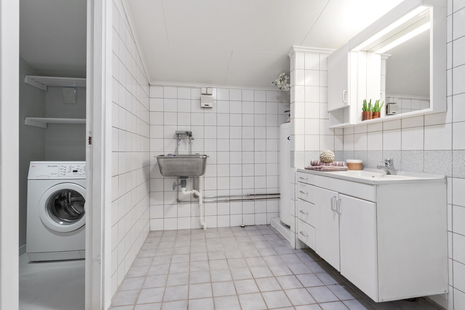 Badet er utstyrt med dusjkabinett, toalett, servantinnredning og utslagsvask. Galleribilde