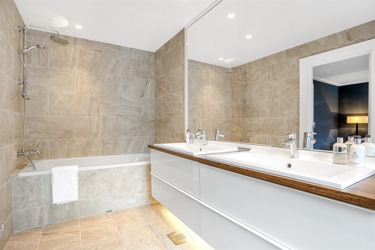 Baderommet tilknyttet hovedsoverommet har badekar, en stilren servantseksjon med to servanter og heltre benkeplate, samt bredt veggspeil. Galleribilde