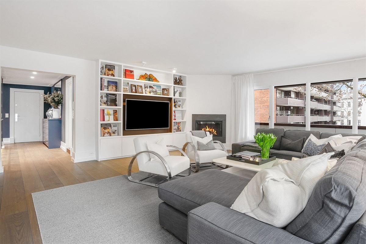 Stuen er luftig med lysinnslipp fra en rekke gode vinduer og har glassdør til veranda. Her er det lett å trives med hygge fra en stilfull peis - et stemningsskapende element. Galleribilde