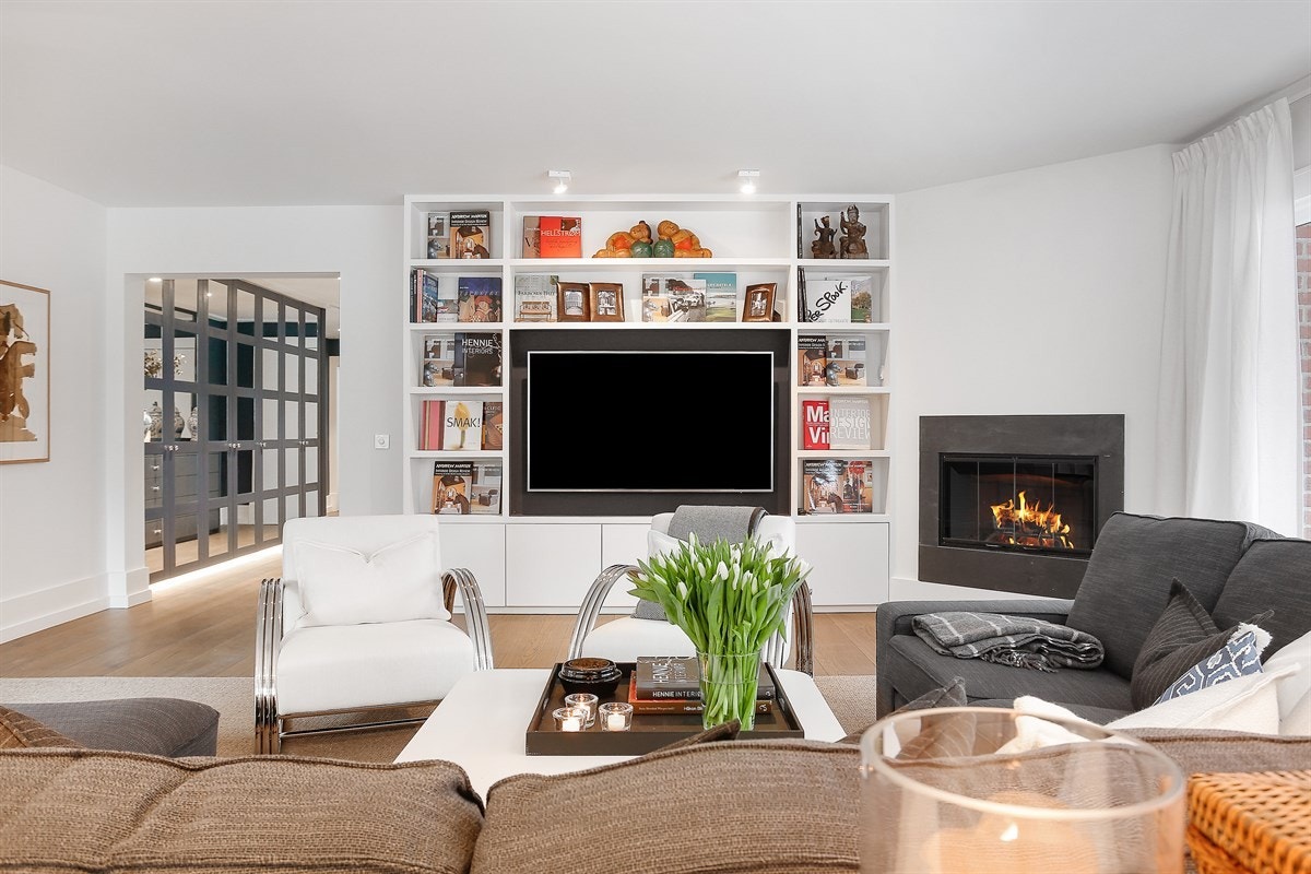 Stuen er luftig med lysinnslipp fra en rekke gode vinduer og har glassdør til veranda. Her er det lett å trives med hygge fra en stilfull peis - et stemningsskapende element. Galleribilde