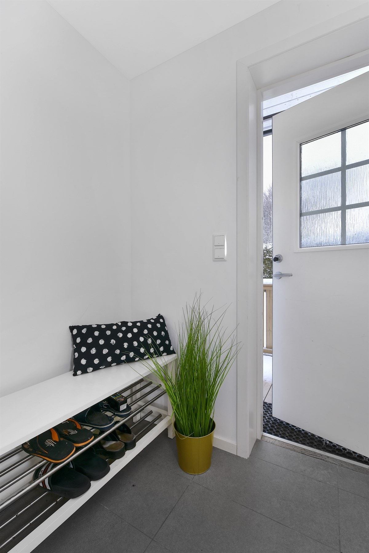 Boligen ønsker deg velkommen inn i en lys, hyggelig entré med flislagt gulv, hvite vegger og plass for garderobeløsninger. Galleribilde