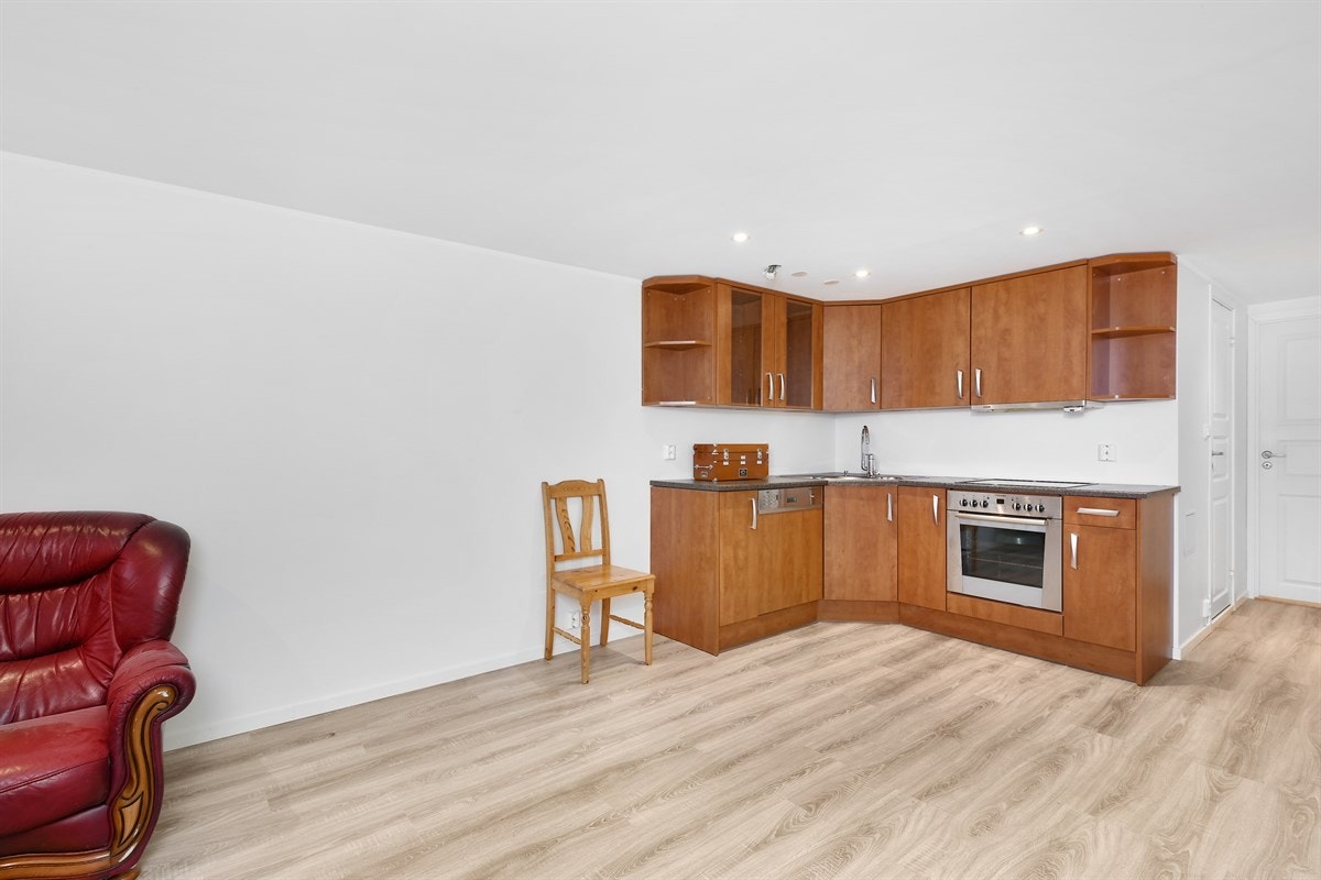 Innredningen har glatte, trefargede fronter, vitrineskap, åpne hyller og benkeplate i laminat med oppvaskkum i stål. Galleribilde