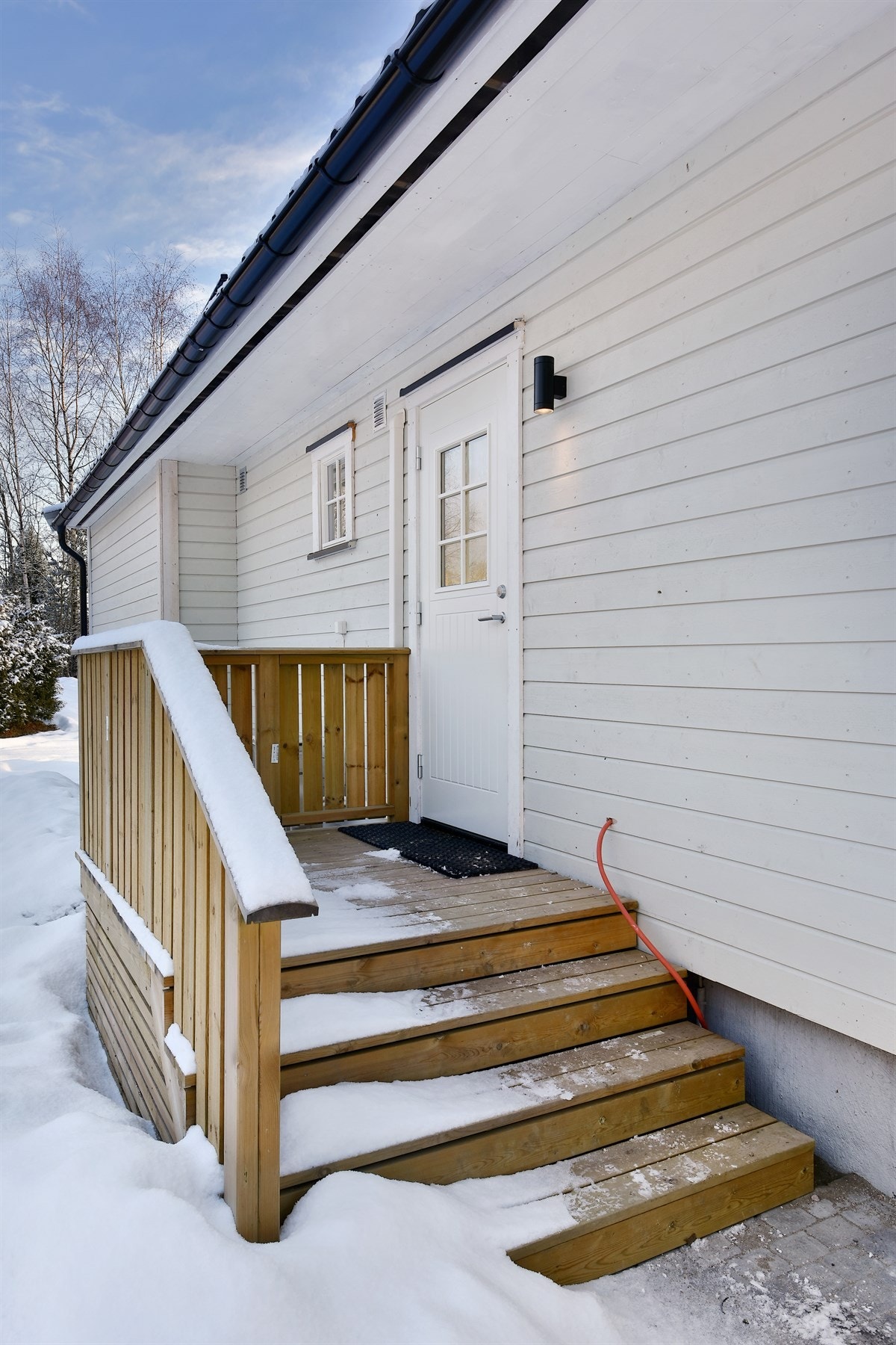 Her er det trapp opp til adkomstterrasse, rekkverk og hvit inngangsdør med glassfelt. Galleribilde