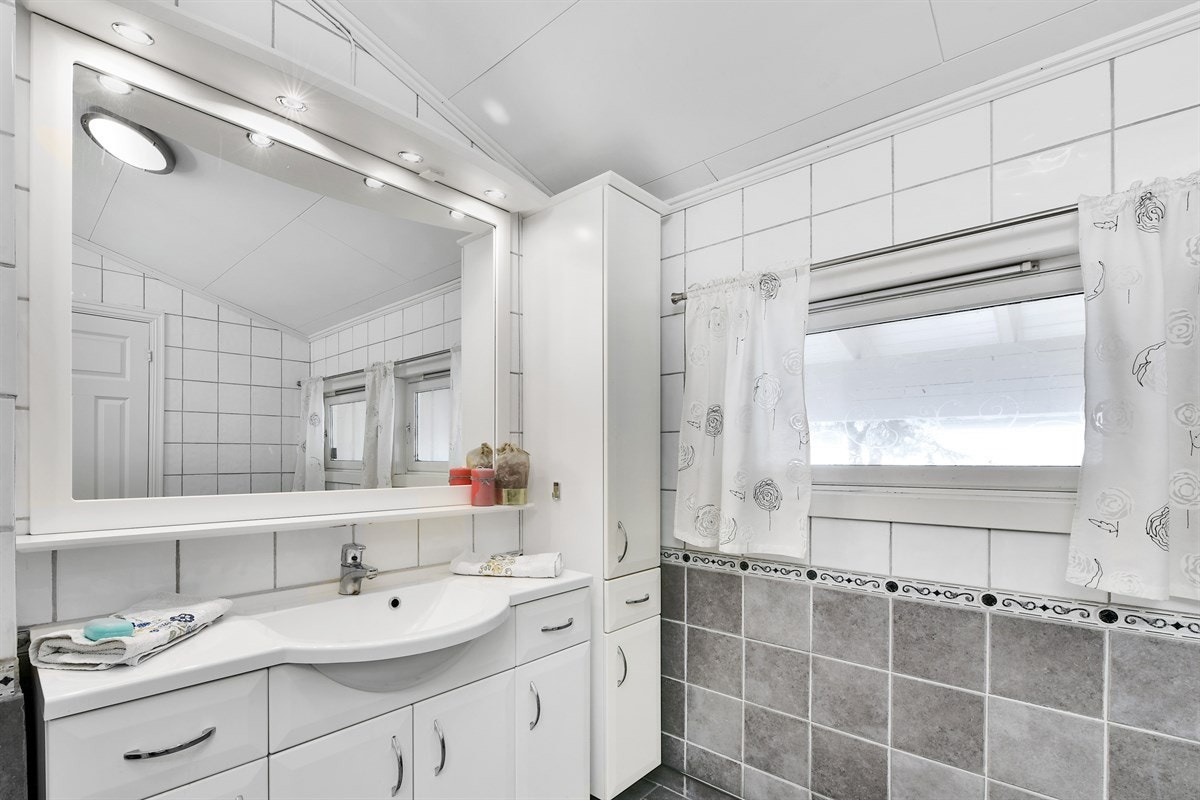 Servant med underskap og høyskap, over servant er det veggspeil med belysning. Galleribilde