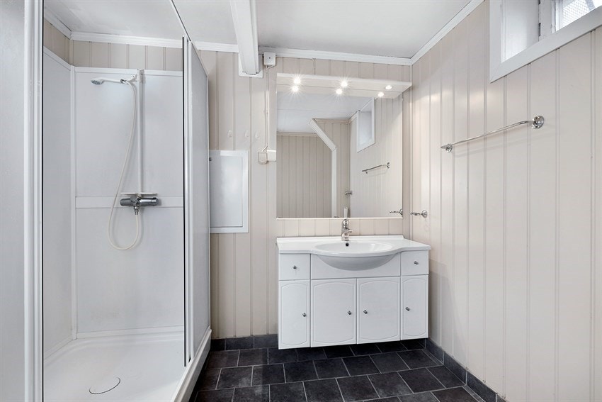 Det andre badet tilhører utleiedelen og har fliser på gulv med underliggende gulvvarme. For øvrig er det panelte vegger i dus farge. Galleribilde