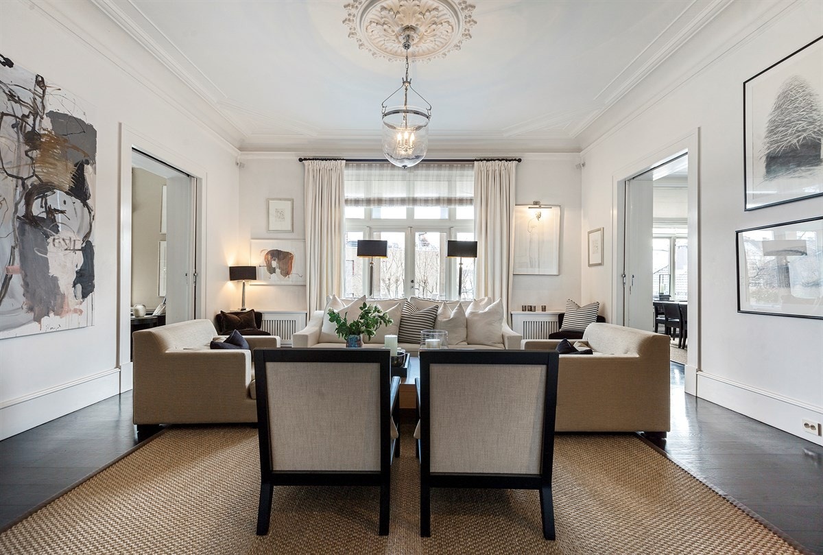 Peisestuen har en tofløyet terrassedør i glass. Utenfor er det en solrik terrasse og adkomst til den private hagen. Peisen er satt i et hjørne, og er innebygd i et sort trepanel. Galleribilde