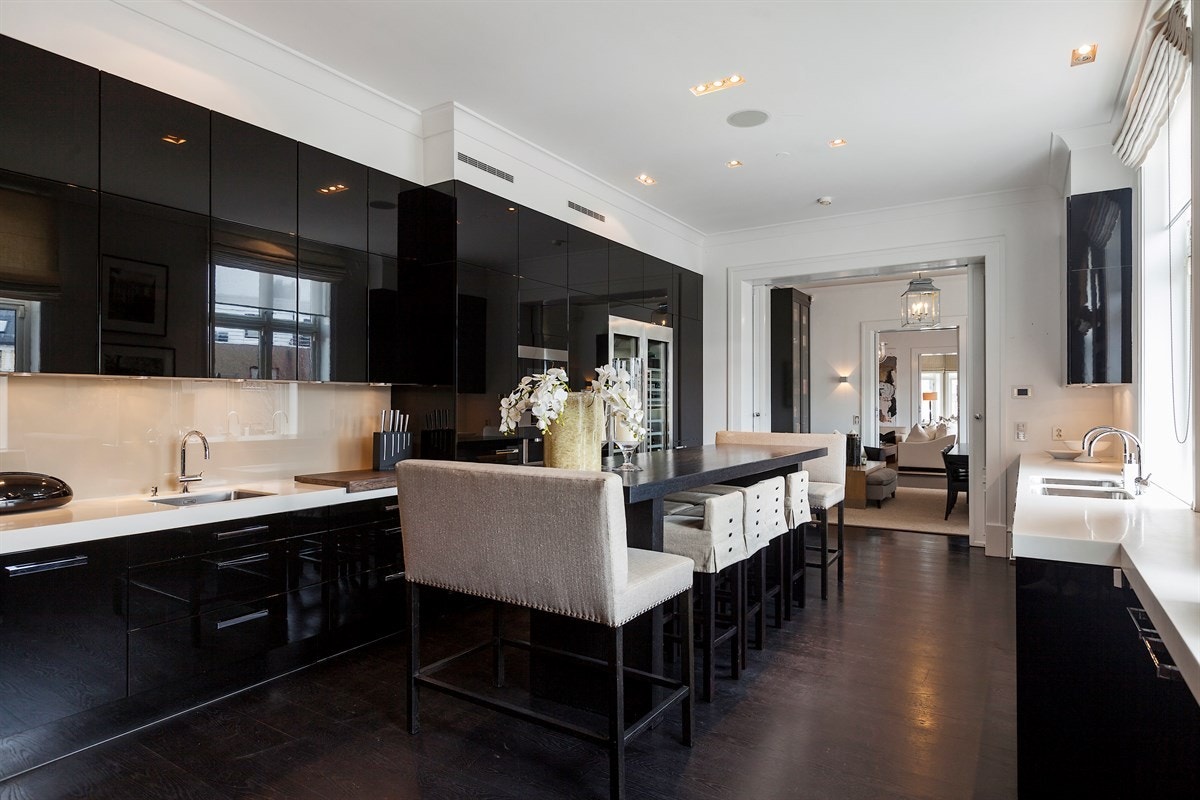 Praktfullt hovedkjøkken med eksklusiv, takhøy innredning fra Poggenpohl i sort høyglans. Benkeplaten er i vakker hvit Corian med tre underlimte oppvaskkummer og tre armaturer. Galleribilde