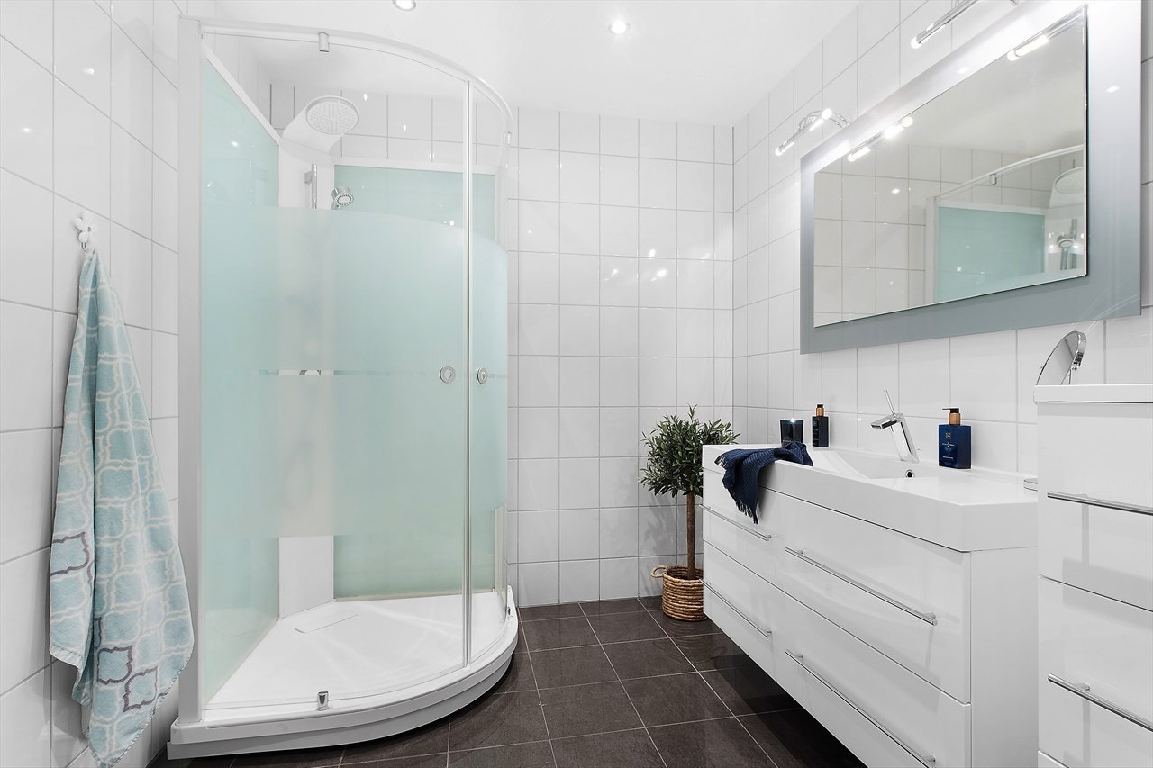 Badet er helfliset med vegghengt toalett, dusj og stort og pent baderomsmøbel. Galleribilde