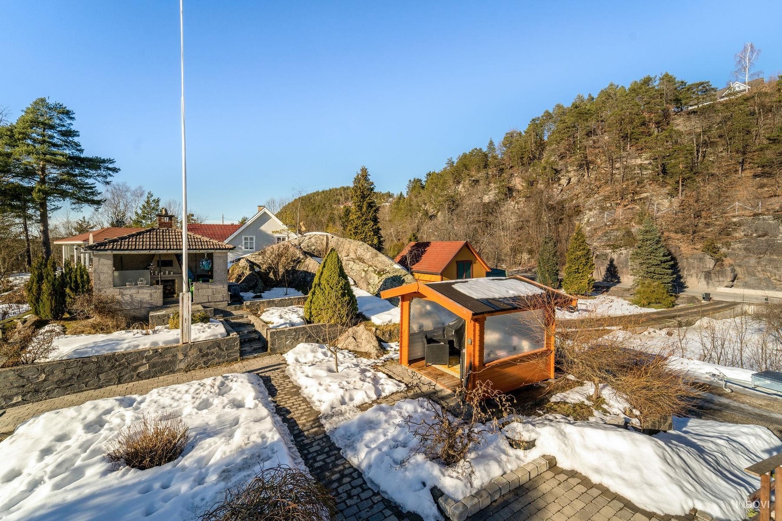 Tomten er romslig og pent opparbeidet med flere nydelige uteplasser. Det er flotte gangstier tillaget med belegingsstein mellom uteplassene. Her er det både murt grillhytte med åpen peis og laftet sommerstue. Galleribilde