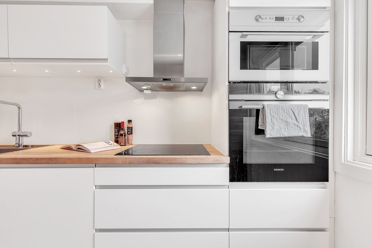 Kjøkken med integrerte hvitevarer og avtrekksvifte ut i friluft. Galleribilde