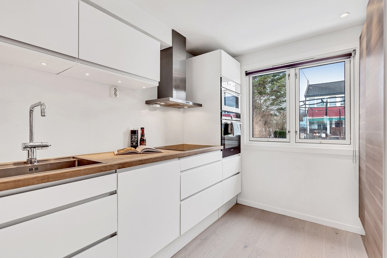 Koselig kjøkken med gode lysforhold med vinduer mot nordøst og naturlig lys og utsyn til hagen både nordvest- og sydvestover. God skap- og benkplass i den pene hvite kjøkkeninnredning fra 2012/13 med glatte skapdører og skuffefronter. Galleribilde