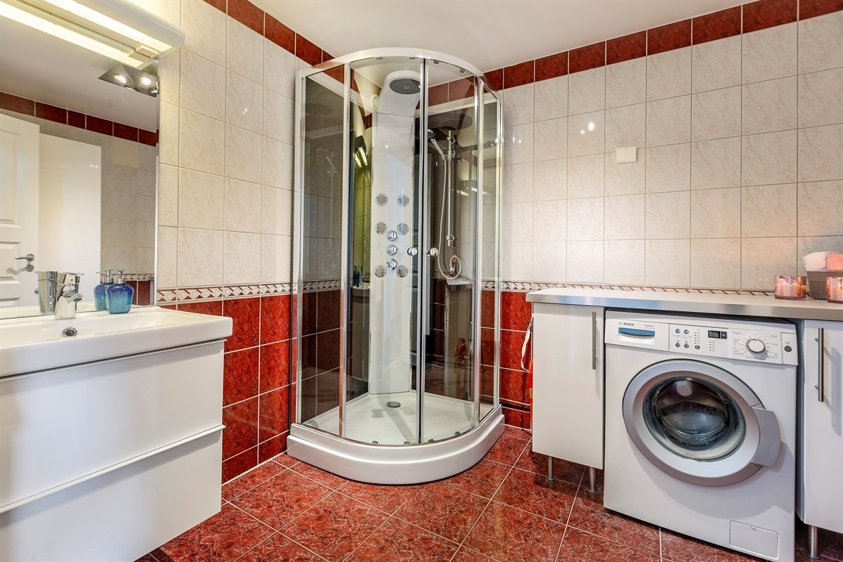 Romslig, flislagt bad med nytt dusjkabinett. Opplegg for vaskemaskin. Galleribilde