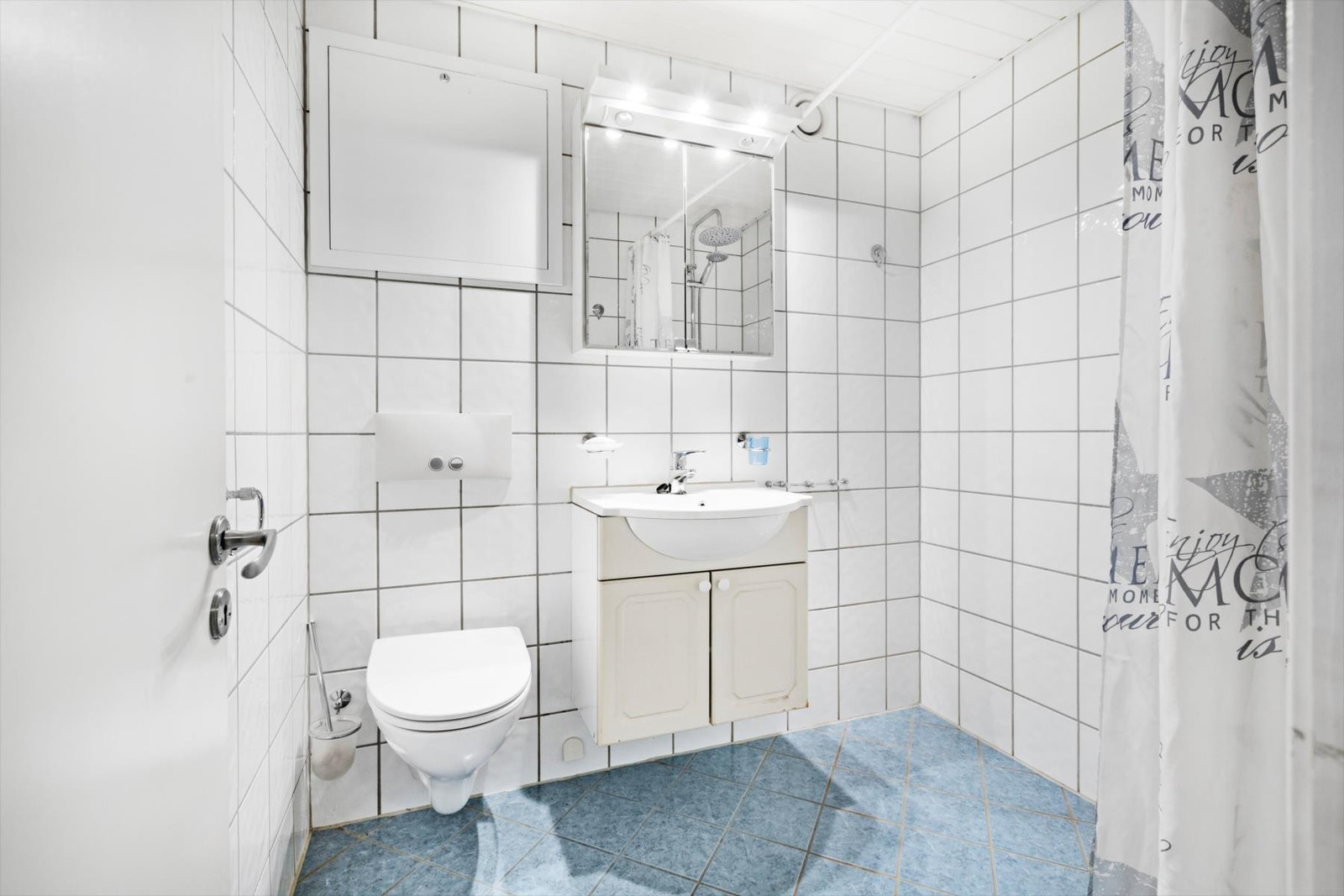 Lyst, flislagt bad med dusjplass, servant med underskap, speil og vegghengt wc. Galleribilde