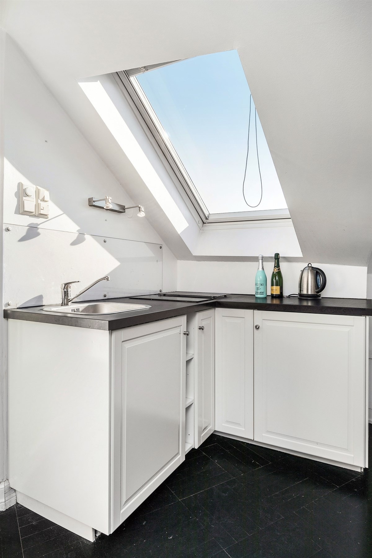 Lys kjøkkeninnredning med laminat benkeplater, profilerte fronter med stålhåndtak og to integrerte kokeplater. Galleribilde