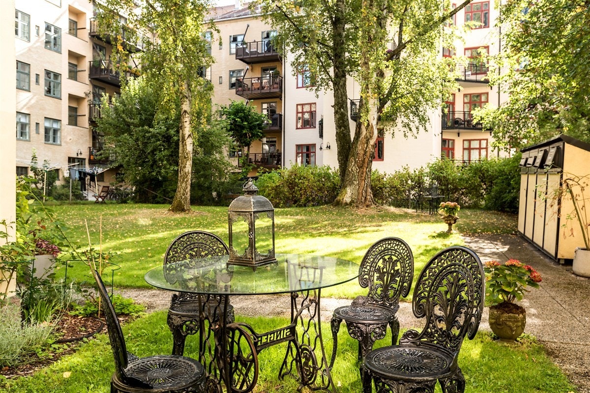 Pent opparbeidet gårdsrom med gressplen, beplantning, trær, sittegruppe m.m. Galleribilde