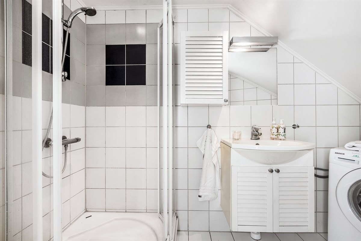 Flislagt bad med toalett, dusjhjørne og servant med underskap. Galleribilde