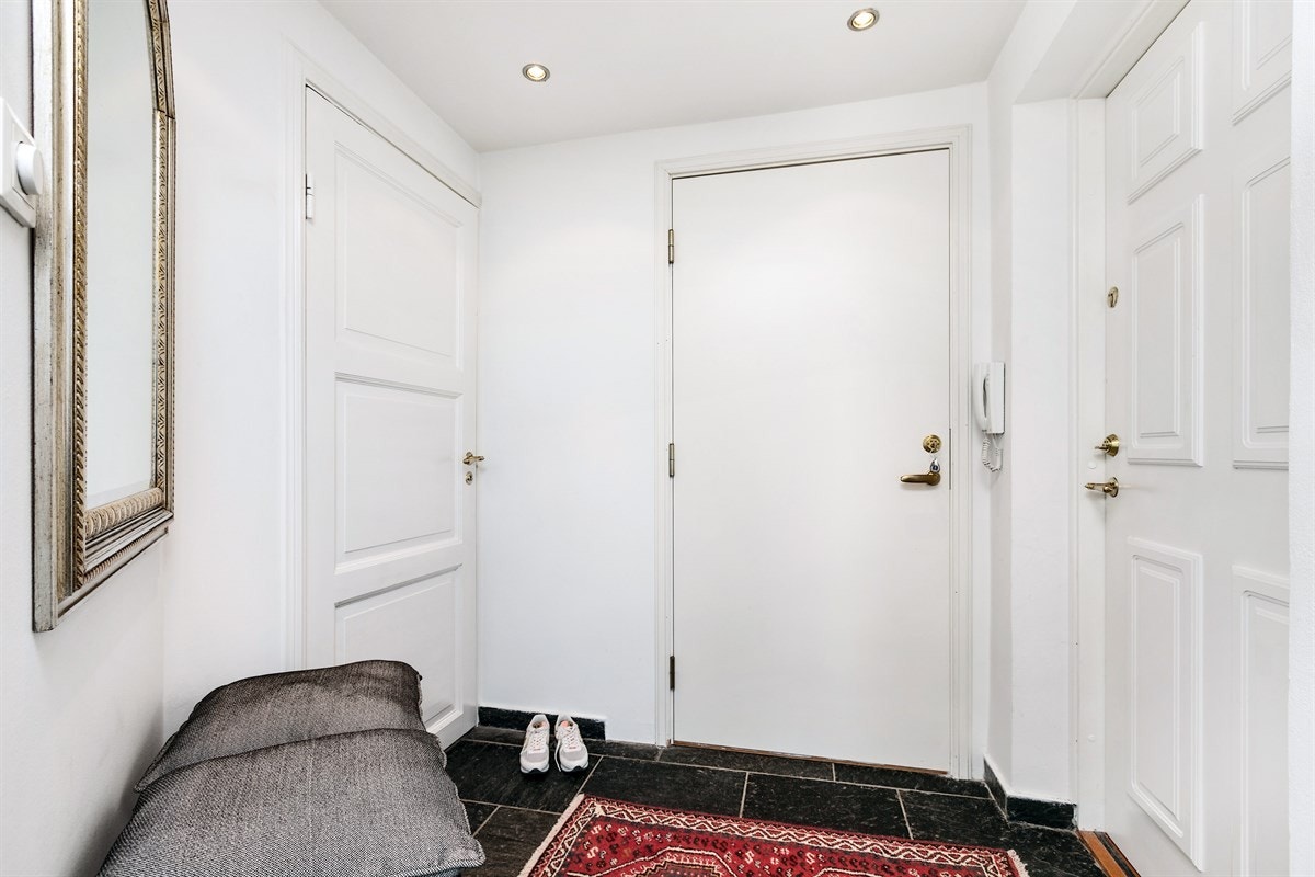 Entré med flotte, mørke skiferfliser på gulv og inngang til et praktisk garderoberom. Galleribilde