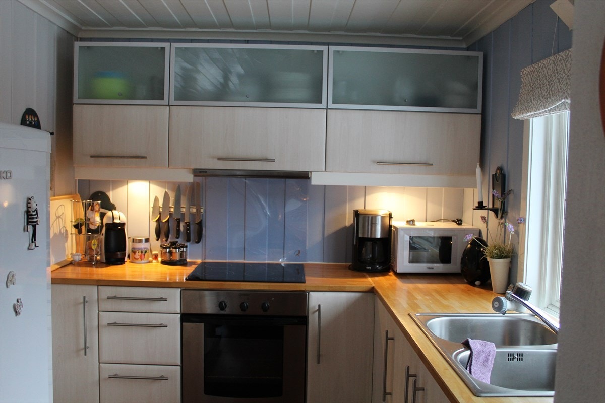 Romslig kjøkken med lyse fronter og heltre benkeplate Galleribilde