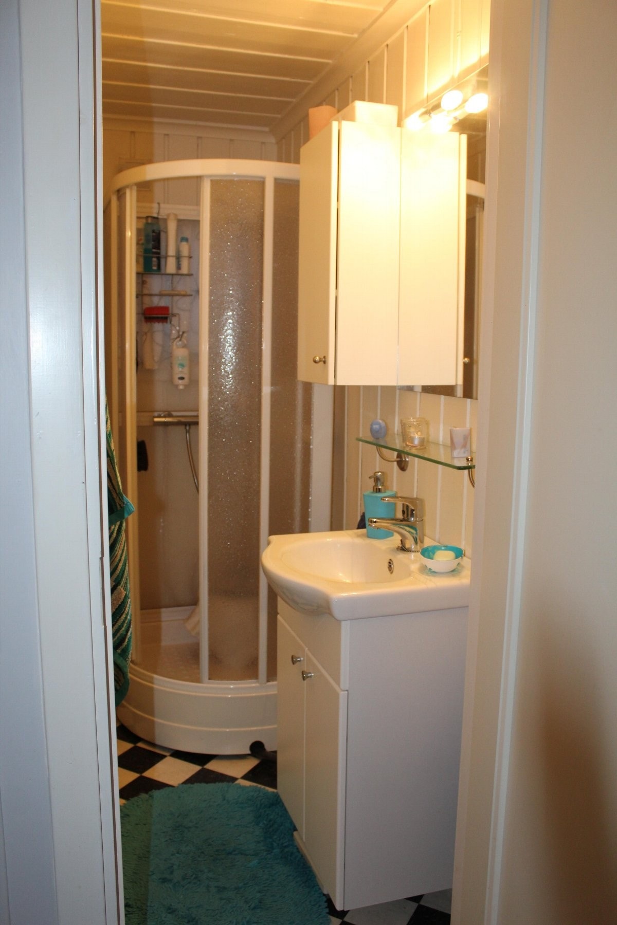 Badet er innredet med dusjkabinett og servantinnredning med tilhørende speil Galleribilde