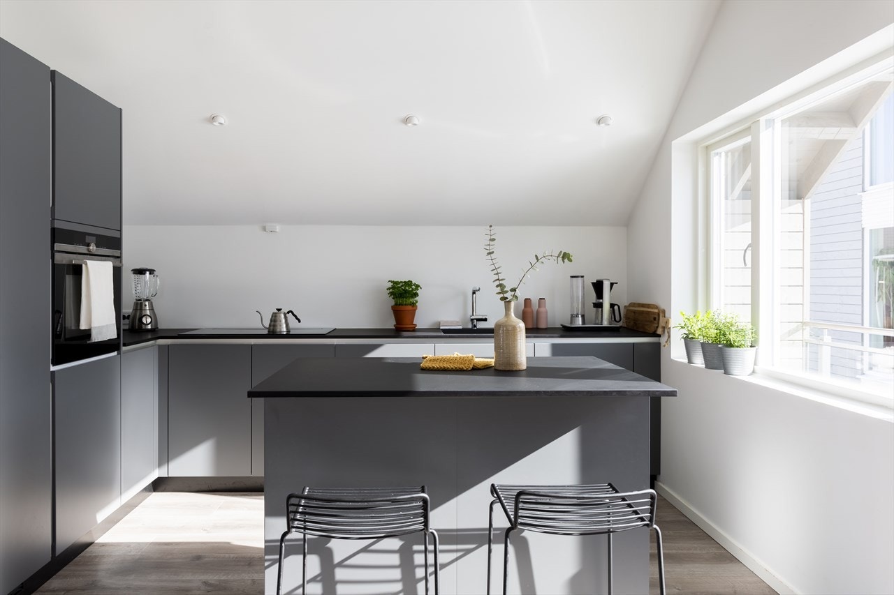 Kjøkkeninnredningen er fra Kvik og har grå, glatte fronter og en mørk, laminert benkeplate med underlimt oppvaskkum. Galleribilde