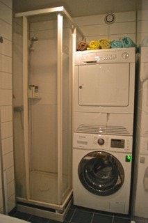 Bad i Moderne utførelse med dusjkabinett og opplegg for vaskemaskin og tørketrommel Galleribilde