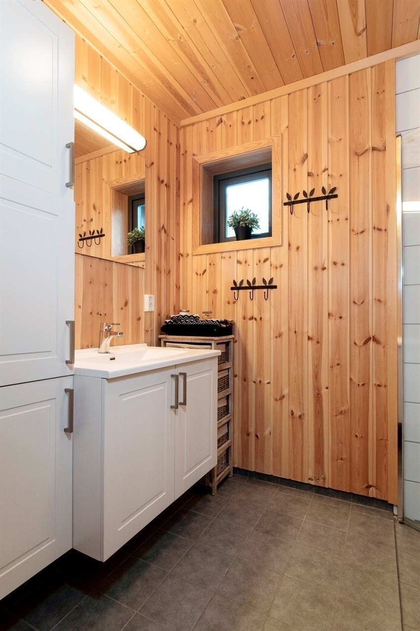 Badet har panel på veggene og flislagt gulv med varme. Det er fliser på veggen i dusjhjørnet Galleribilde