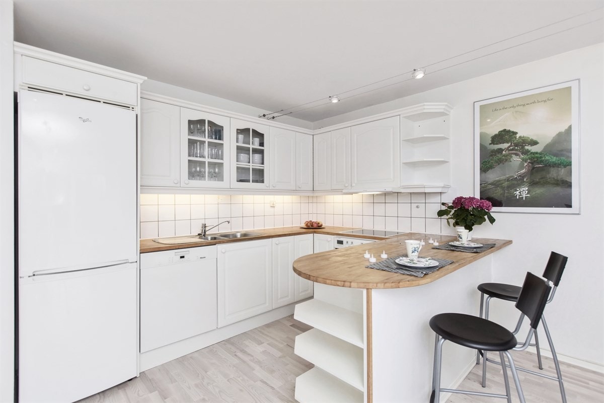 Pent og funksjonelt kjøkken med åpen løsning ut mot stue. Godt med benkeplass og oppbevaringsplass i flere overskap og underskap med skuffer. Galleribilde