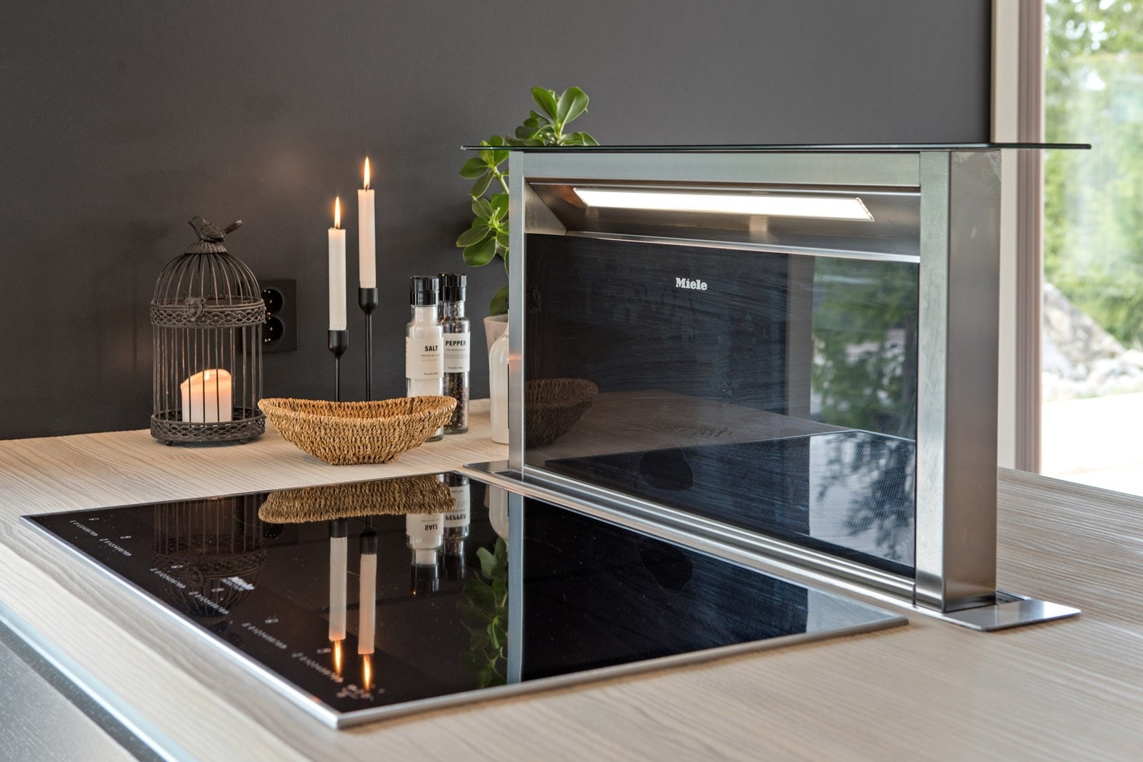 Det følger integrert induksjonsplatetopp i 70 mm tykk plate, samt nedfelt avtrekksvifte, som styres via sortfarget styringspanel. Galleribilde