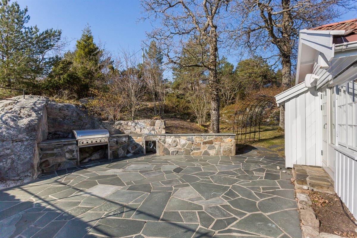 Fra den usjenerte og solrike uteplassen - med utekjøkken med grill og kjøleskap Galleribilde