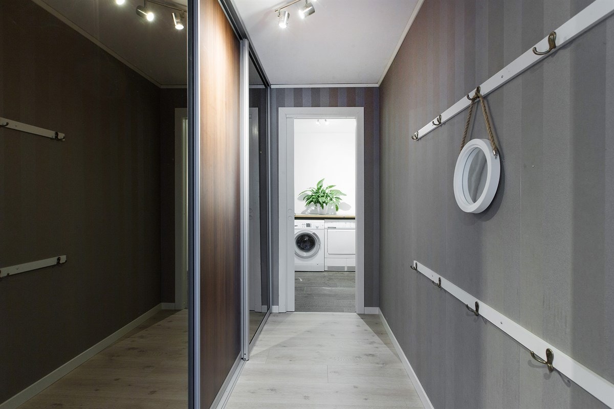 Mellomgangen fra entréen til vaskerommet langstrakt med romslig skyvedørsgarderobe. Galleribilde