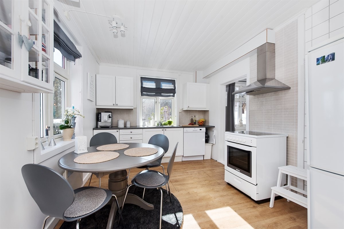 Kjøkkenet er innredet med hvite profilerte eikefronter og laminert benkeplate med nedfelt dobbel oppvaskkum. Galleribilde