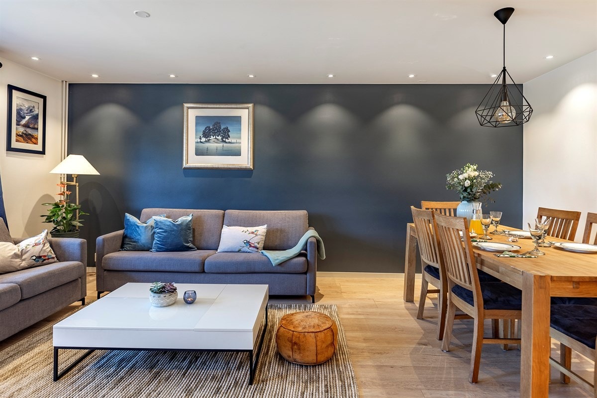Stuen har en fondvegg i mørkeblå fargetone. Galleribilde