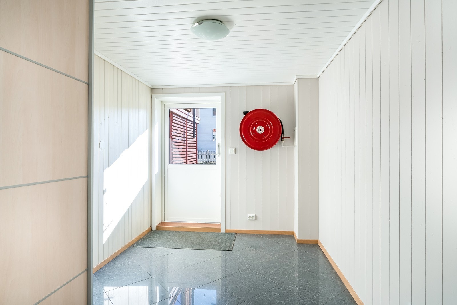 Gang i kjeller med fliser og garderobeskap. Kun få trappetrinn til bakkeplan. Galleribilde