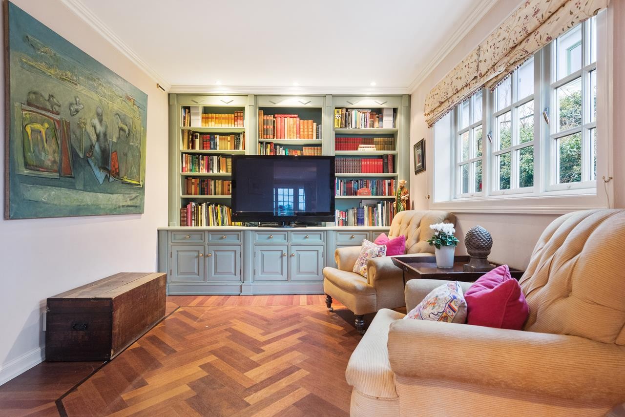 Innenfor stuen ligger et lunt og koselig tv-rom med plassbygget bokhylle. Galleribilde