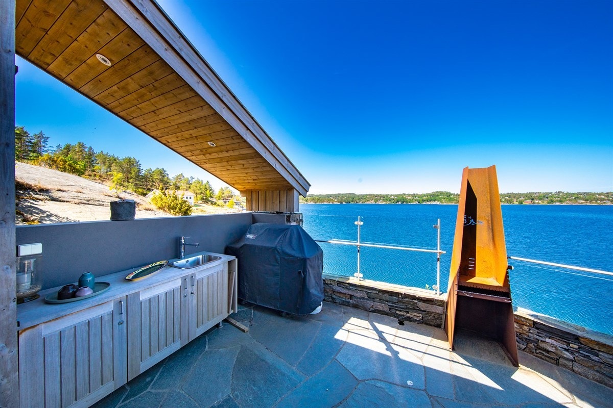 Mot vest ligger en stor skiferbelagt terrasse med eget utekjøkken. Galleribilde