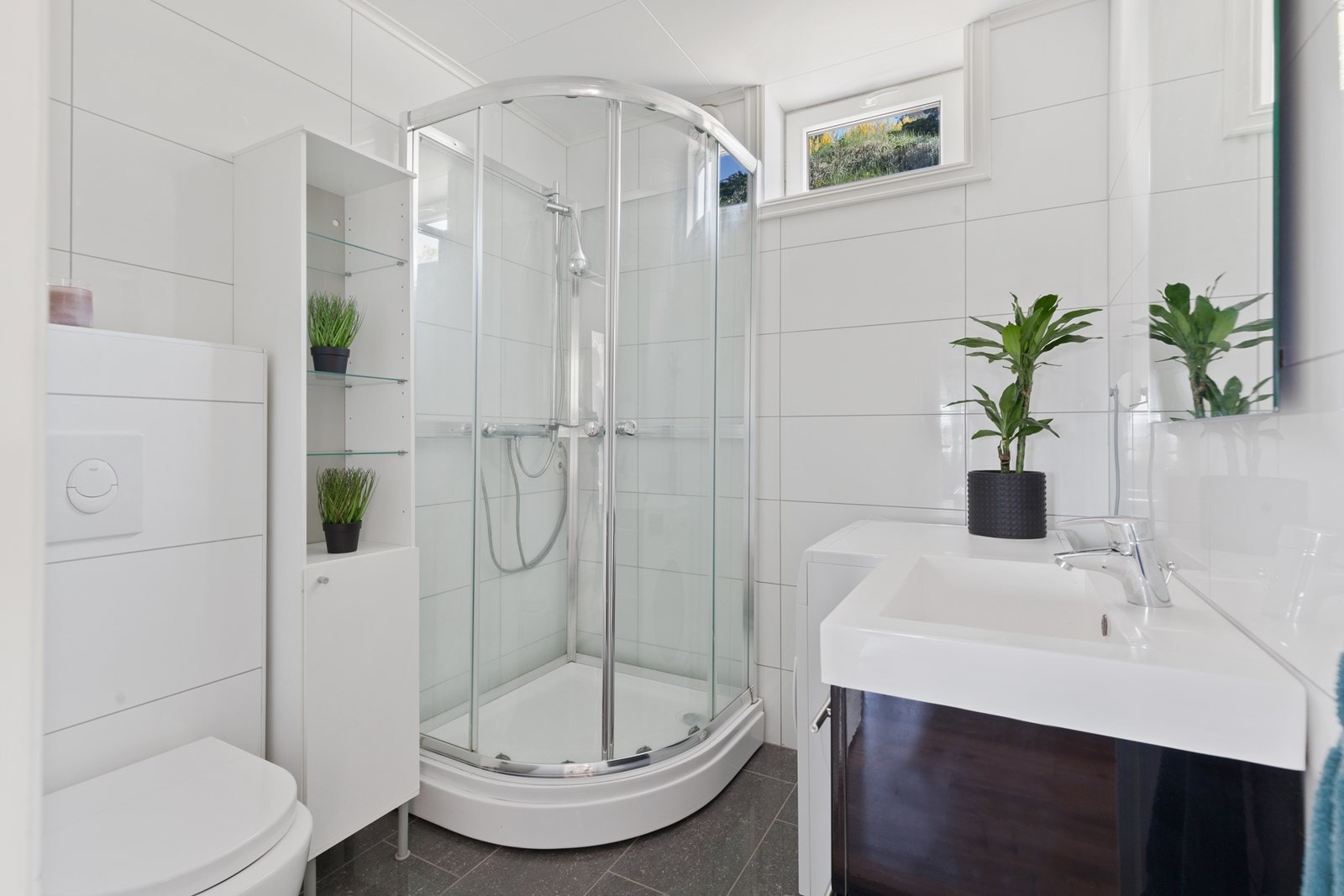 Bad hybel er også flislagt med gulvvarme. Rommet er innredet med baderomsinnredning, dusjkabinett, WC og opplegg til vaskemaskin. Galleribilde