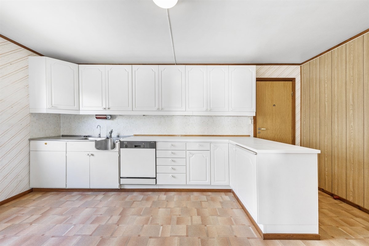 Kjøkkenet har innreiing medmåla frontar samansett av eldre benkeskåp med stålbeslag og nyare skåp med profilerte frontar Galleribilde