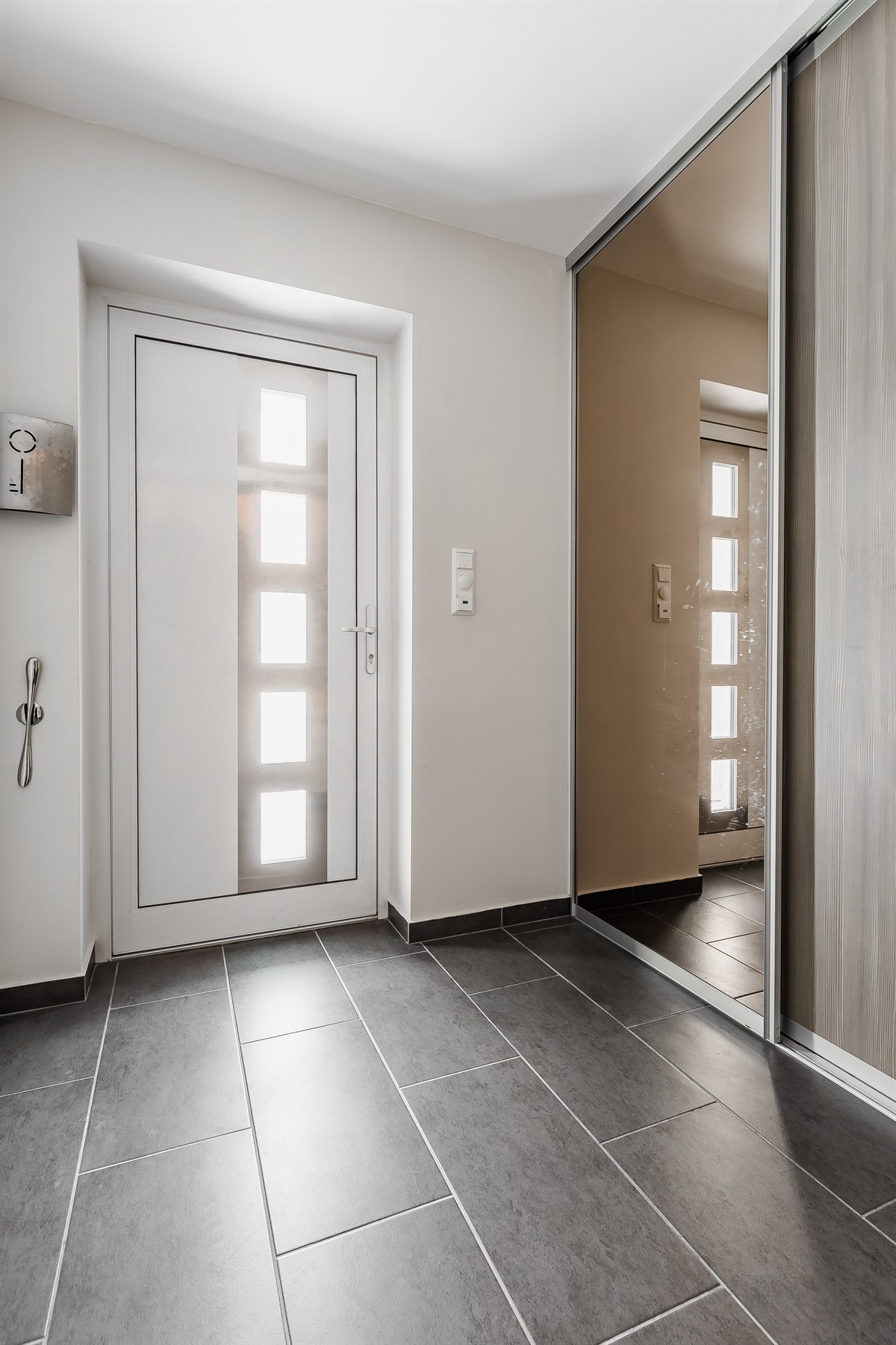 Entré med fliser på gulv og romslig skyvedørsgarderobe
