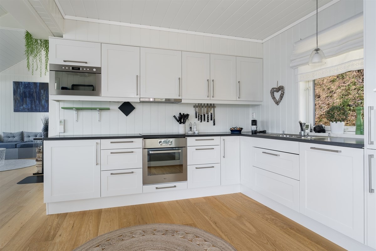 Kjøkken med lys innredning og integrerte hvitevarer. Galleribilde