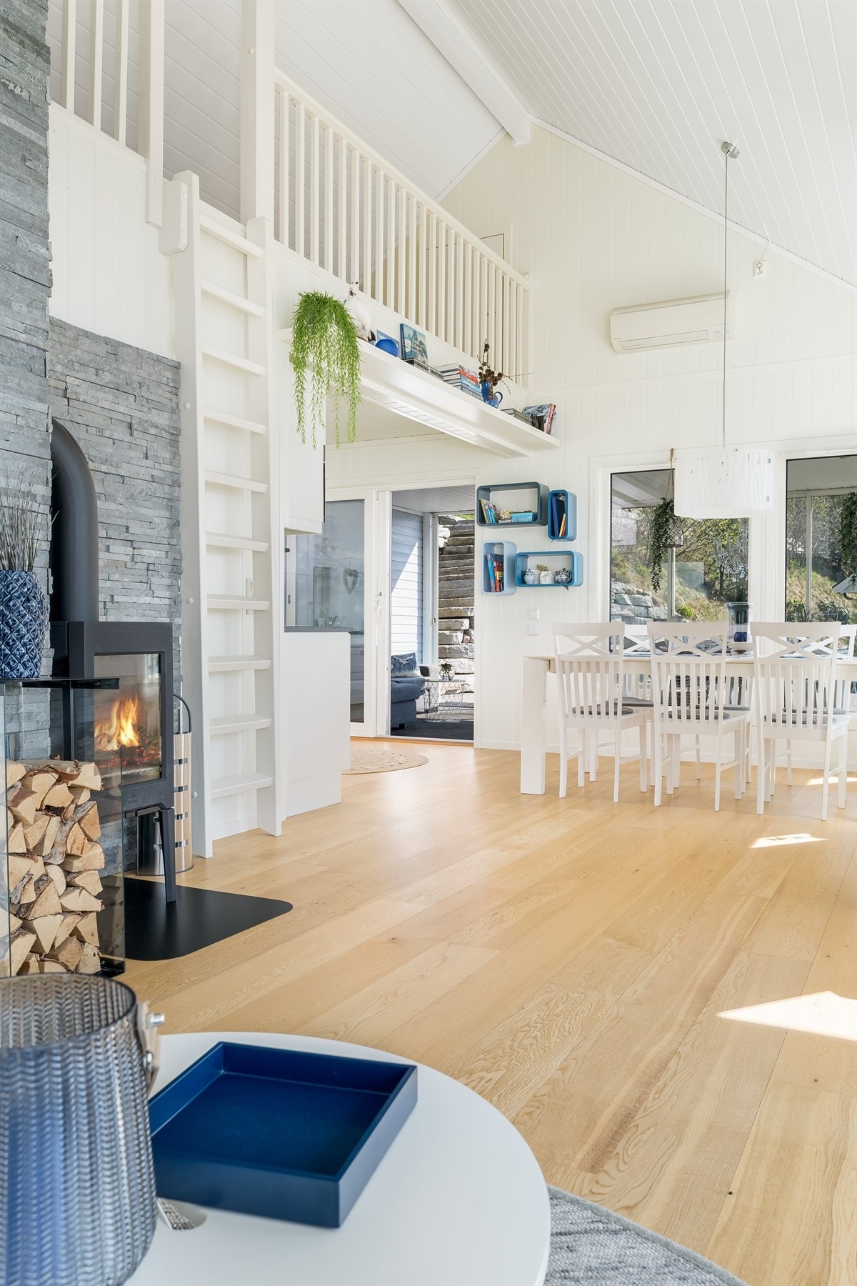 Stue med vedovn. Varmepumpe over spisestuen. Galleribilde