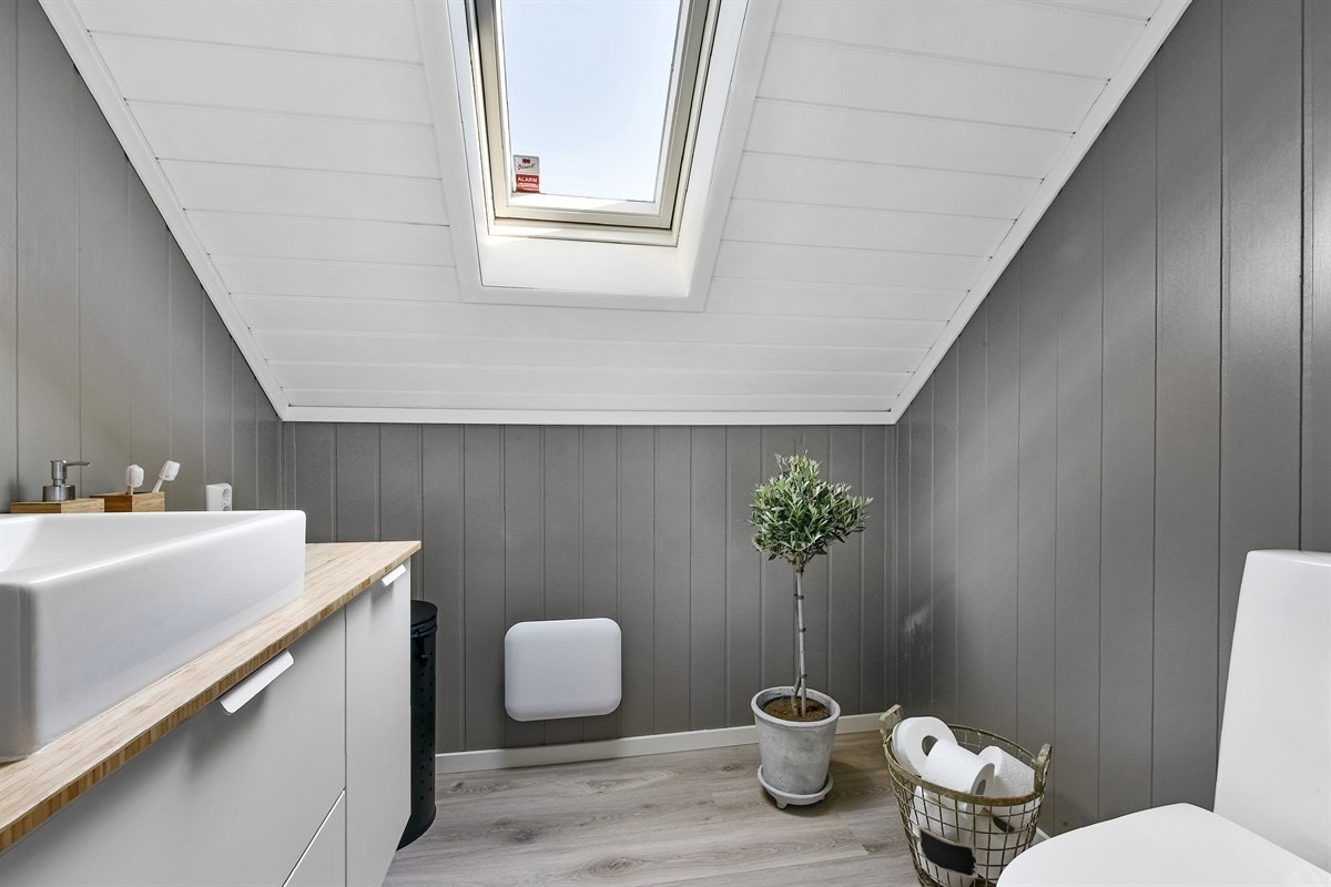 Wc-rommet har grått smartpanel på veggene, hvitmalt panel i himling og laminat på gulvet. Galleribilde