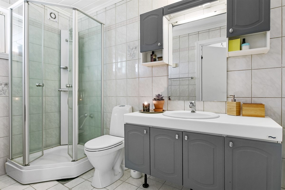 Badet har lyse fliser på vegger og gulv, og det har varme i gulvet og hvitmalt panel i himlingen. Galleribilde