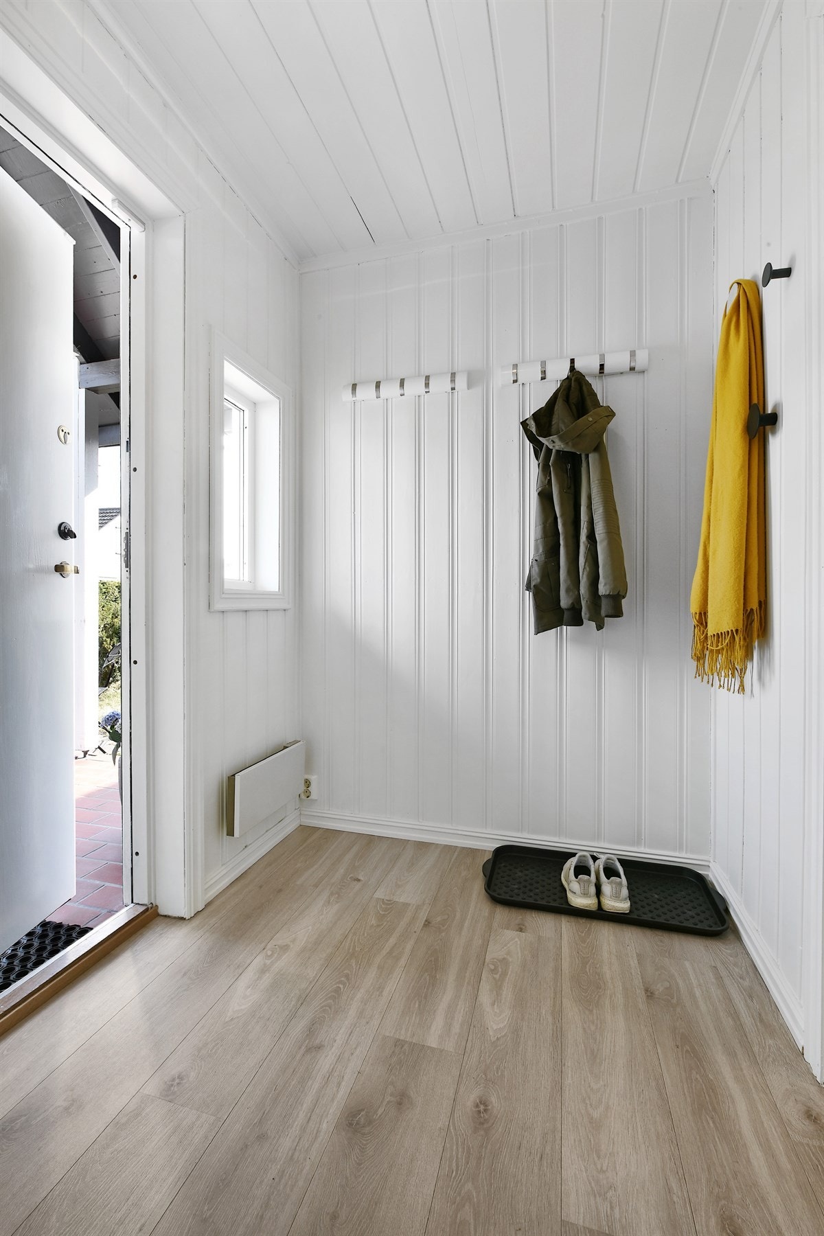 Entreen har vegger som er malt i en moderne gråfarge, og på gulvet er det sandfargede fliser og gulvvarme. Det er plass til mindre oppbevaringsmøbler. Galleribilde