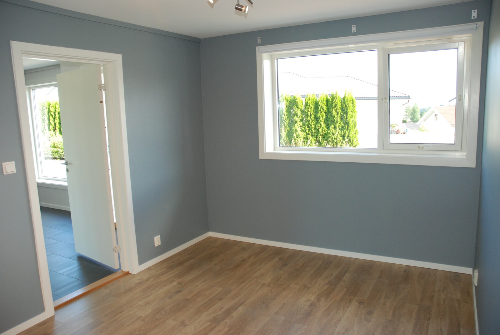 Soverom med lun farge og stort vindu som gir godt med lys og mulighet for lufting Galleribilde