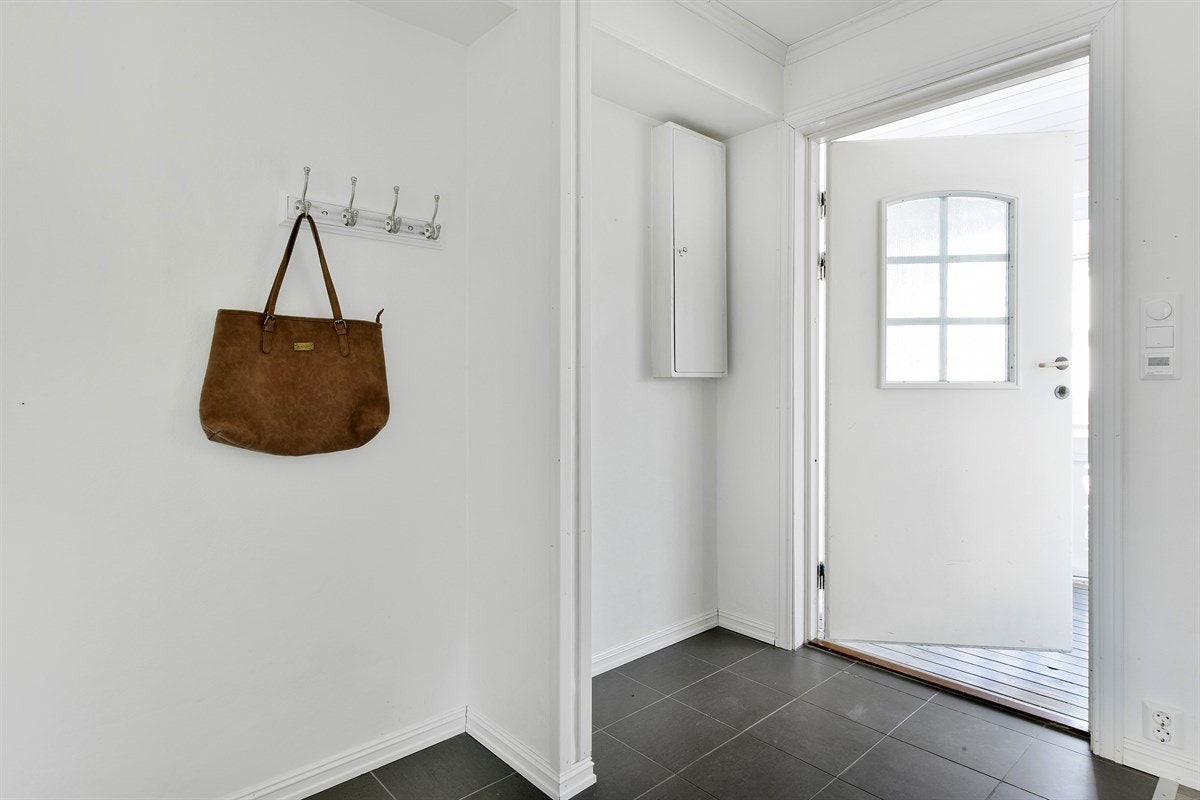 Rommet er innredet med blant annet mørke gulvfliser ved ytterdør, parkettlaminat og åpen garderobeløsning, og på vegg er det en tidsriktig hvitfarge som harmonerer med øvrige rom. Galleribilde