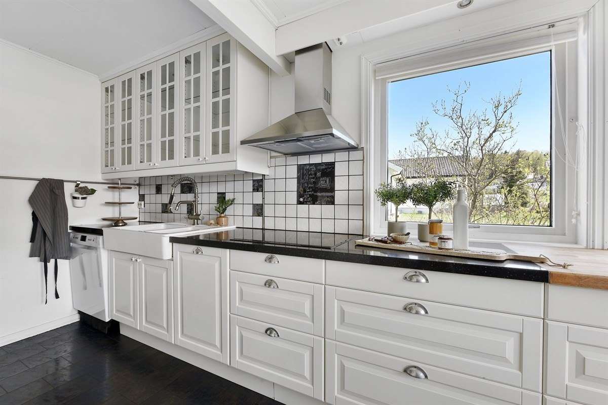 Innredningen er takhøy og har hvite, profilerte fronter, flere vitrineskap og lyse fliser over benk. Galleribilde