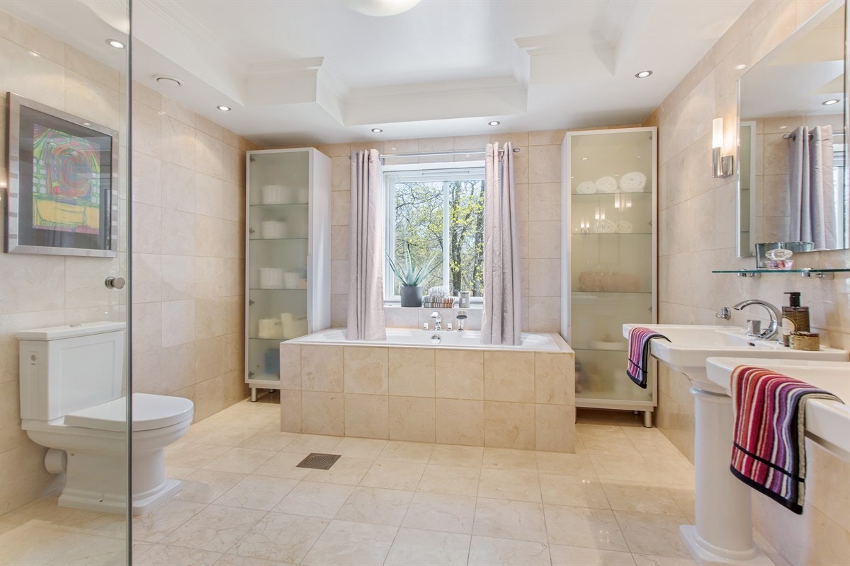 Bad tilhørende master bedroom. Badet ble rehabilitert i ca 2001 og inneholder bl.a. badekar fra Villeroy & Boch, dusj med 5 dyser, wc og 2 stk. søyleservanter i hvit porselen Galleribilde